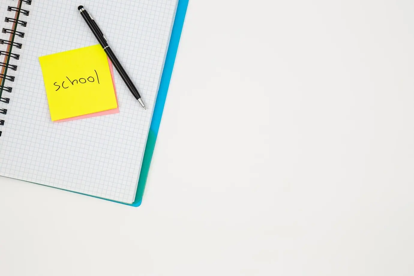 Notizbuch, Stift und Papier sowie farbige Erinnerungszettel auf weißem Hintergrund.